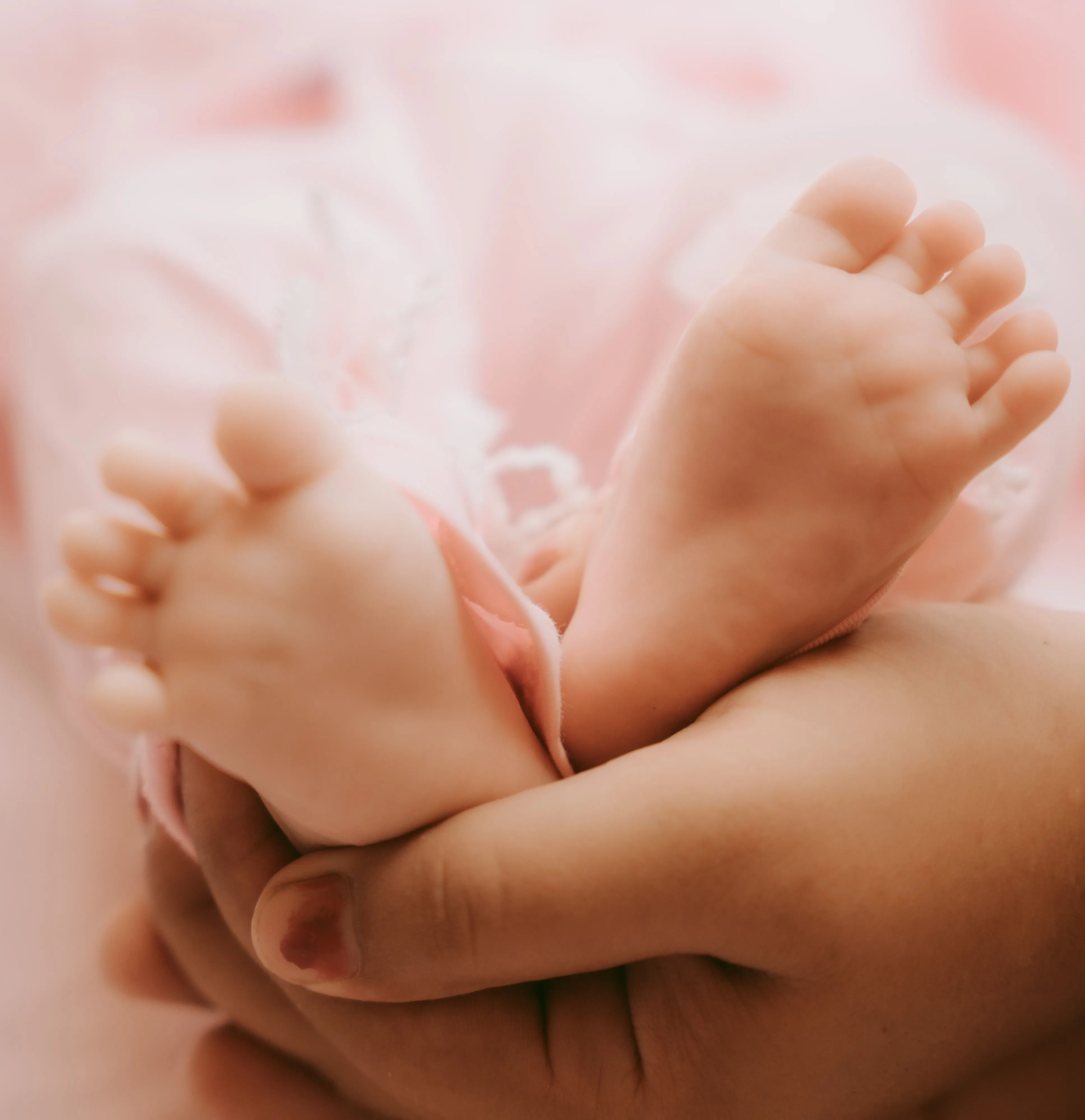 Caring hands gently holding a newborn baby's feet, representing compassionate surrogacy support in Georgia